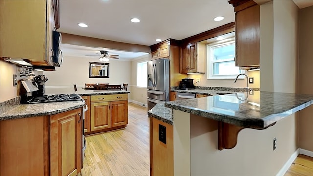 kitchen featuring sink, a kitchen breakfast bar, stainless steel appliances, light hardwood / wood-style floors, and kitchen peninsula