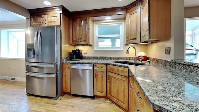 kitchen with dark stone countertops, sink, a healthy amount of sunlight, and appliances with stainless steel finishes