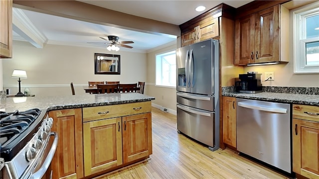 kitchen with ornamental molding, stainless steel appliances, light hardwood / wood-style flooring, and dark stone counters