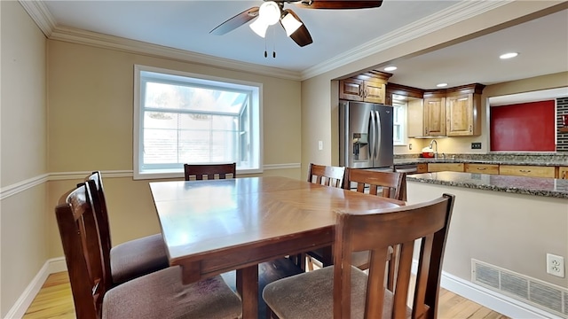 dining area with ceiling fan, ornamental molding, sink, and light wood-type flooring