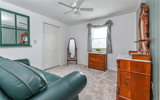 living area with ceiling fan, light colored carpet, and a textured ceiling