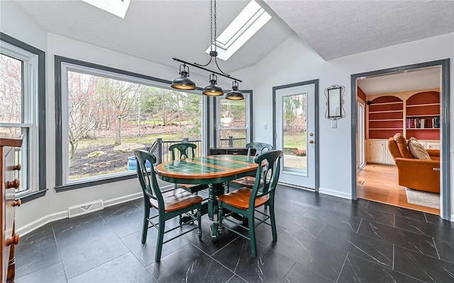 dining room with a textured ceiling, lofted ceiling with skylight, and a healthy amount of sunlight