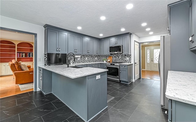 kitchen featuring appliances with stainless steel finishes, gray cabinets, sink, and kitchen peninsula