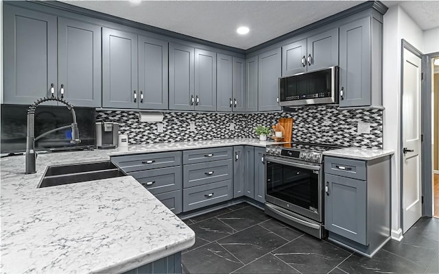 kitchen with stainless steel appliances, sink, and gray cabinetry