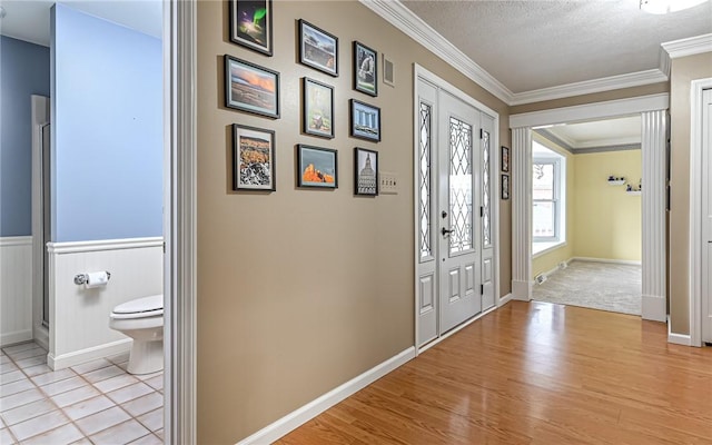 entryway with crown molding, light hardwood / wood-style flooring, and a textured ceiling