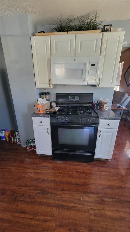 kitchen featuring dark wood-type flooring, white cabinetry, and black gas range