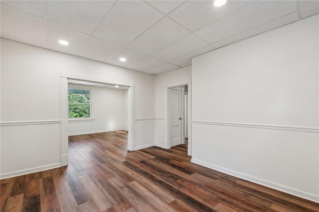 unfurnished room with dark hardwood / wood-style flooring and a drop ceiling