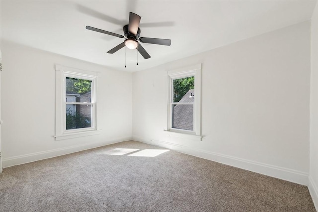 carpeted spare room featuring ceiling fan and a wealth of natural light