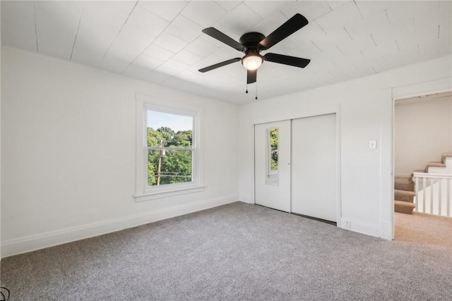 unfurnished bedroom featuring carpet, ceiling fan, and a closet