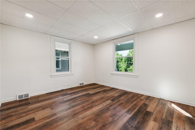 spare room featuring dark wood-type flooring and a drop ceiling