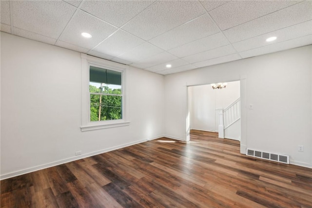 spare room with dark hardwood / wood-style flooring and a paneled ceiling