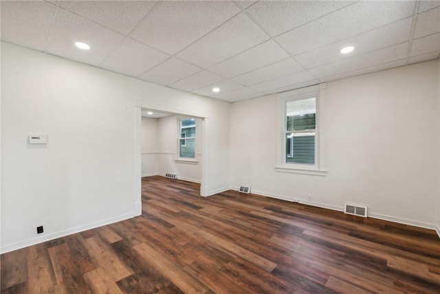 empty room with dark hardwood / wood-style floors and a drop ceiling