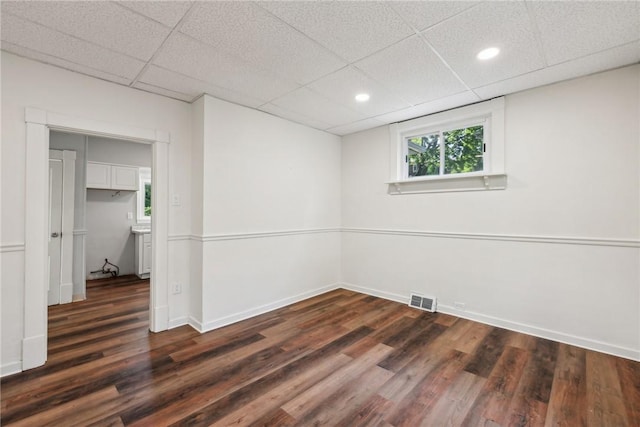 empty room with dark hardwood / wood-style floors and a drop ceiling