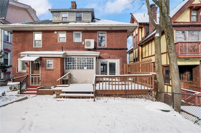 snow covered back of property featuring a wooden deck and ac unit