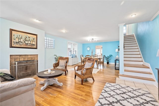 living room featuring a tiled fireplace and light hardwood / wood-style floors