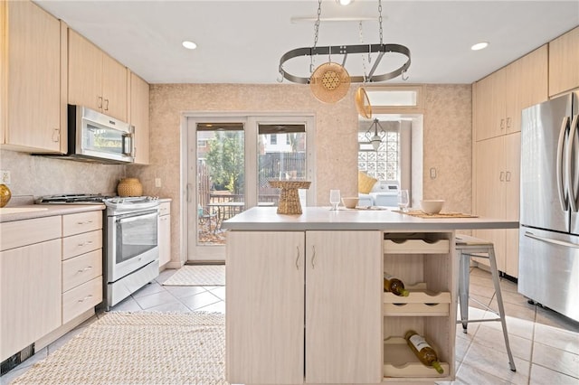 kitchen with light brown cabinetry, decorative light fixtures, a center island, and appliances with stainless steel finishes