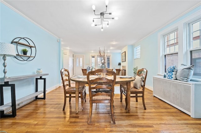 dining room featuring crown molding, a chandelier, radiator heating unit, and light wood-type flooring