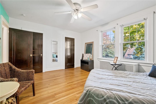 bedroom with radiator heating unit, light hardwood / wood-style flooring, and ceiling fan