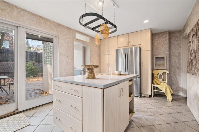 kitchen with stainless steel refrigerator, light brown cabinetry, a kitchen island, and light tile patterned floors