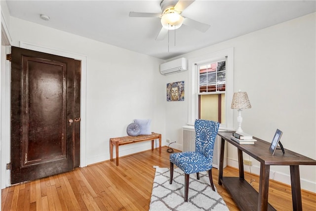 living area featuring light hardwood / wood-style flooring, an AC wall unit, and ceiling fan