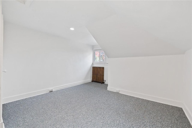 additional living space with lofted ceiling, radiator heating unit, and carpet floors