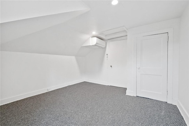 additional living space with dark colored carpet, vaulted ceiling, and a wall unit AC