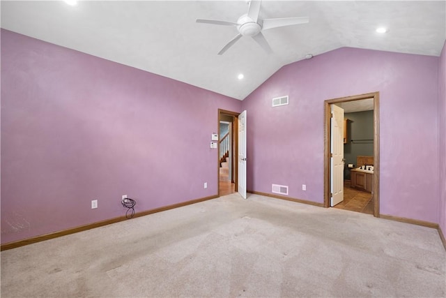 unfurnished bedroom featuring ceiling fan, lofted ceiling, light colored carpet, and ensuite bath