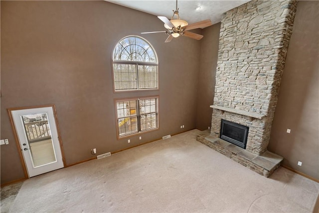 carpeted living room featuring a fireplace, ceiling fan, and a high ceiling