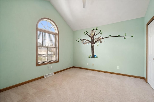 carpeted spare room with vaulted ceiling