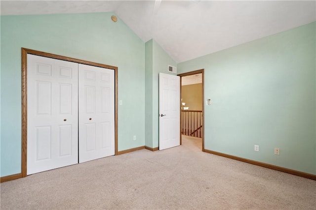 unfurnished bedroom featuring vaulted ceiling, light colored carpet, and a closet