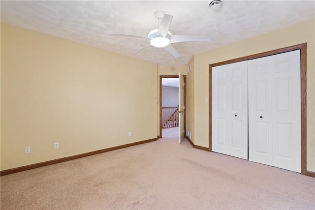 unfurnished bedroom featuring light colored carpet, a closet, and ceiling fan