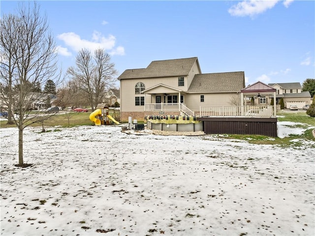 snow covered house featuring a playground