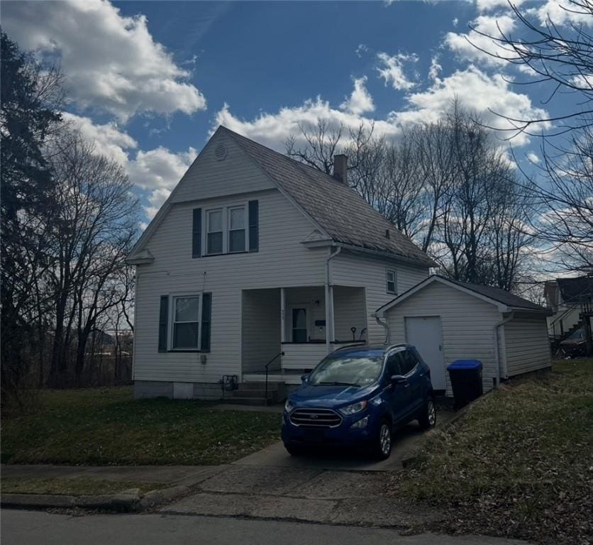 view of front of house with a chimney, concrete driveway, covered porch, and a front yard