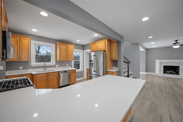 kitchen with sink, appliances with stainless steel finishes, kitchen peninsula, ceiling fan, and light hardwood / wood-style floors