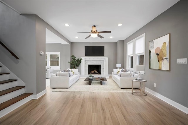 unfurnished living room with baseboards, a tiled fireplace, stairway, and wood finished floors