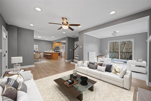 living area featuring stairs, light wood-type flooring, baseboards, and recessed lighting