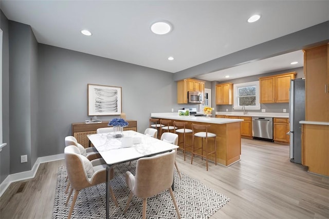 dining area with light wood-style floors, baseboards, and recessed lighting