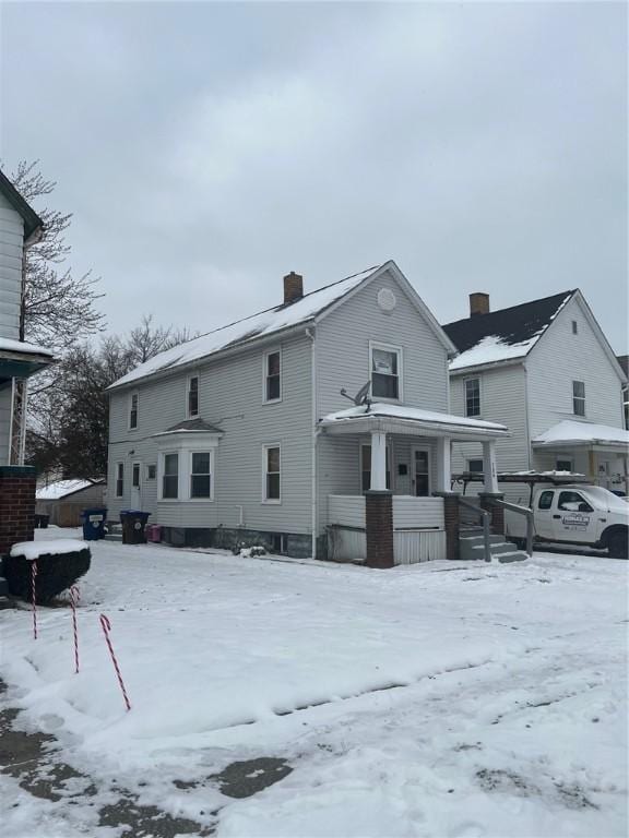 snow covered rear of property with covered porch