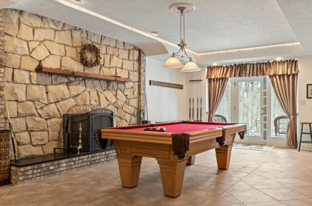 game room with pool table, a fireplace, a raised ceiling, and light tile patterned floors