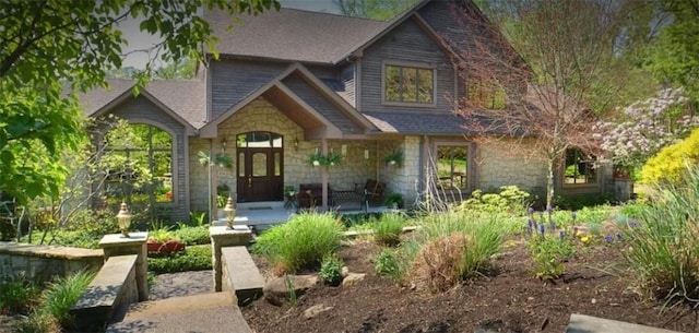 view of front of home featuring stone siding and roof with shingles