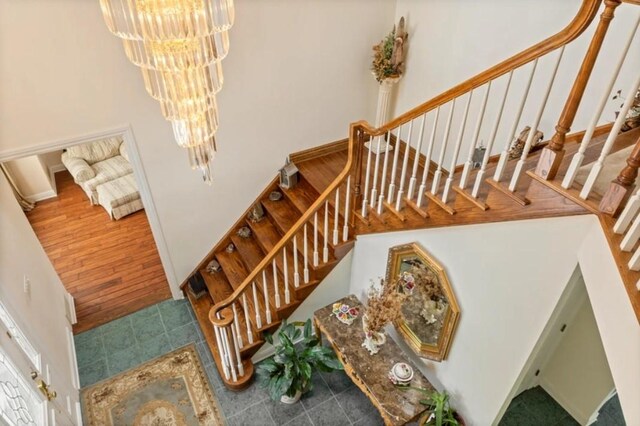 stairs with hardwood / wood-style flooring and a notable chandelier