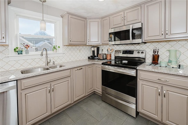 kitchen featuring sink, light stone counters, light tile patterned floors, pendant lighting, and stainless steel appliances