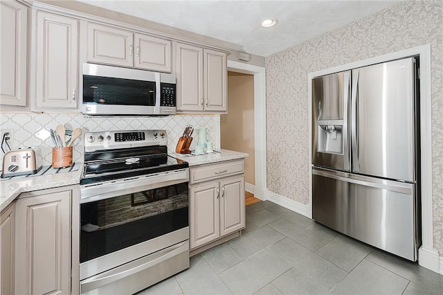 kitchen featuring light tile patterned flooring, appliances with stainless steel finishes, and backsplash