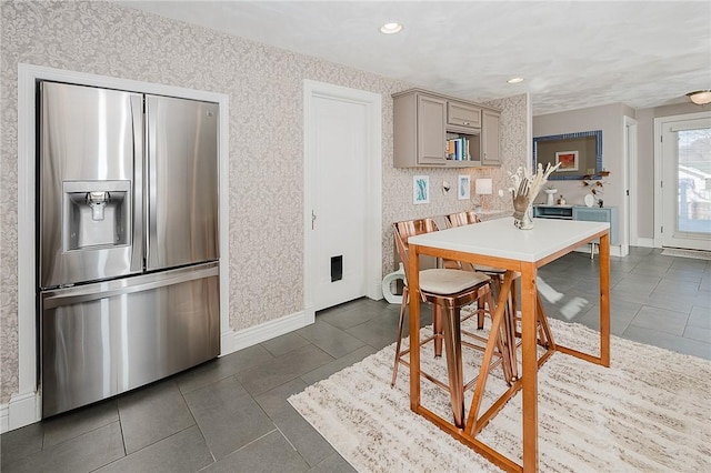 kitchen with gray cabinetry, stainless steel fridge, and dark tile patterned flooring