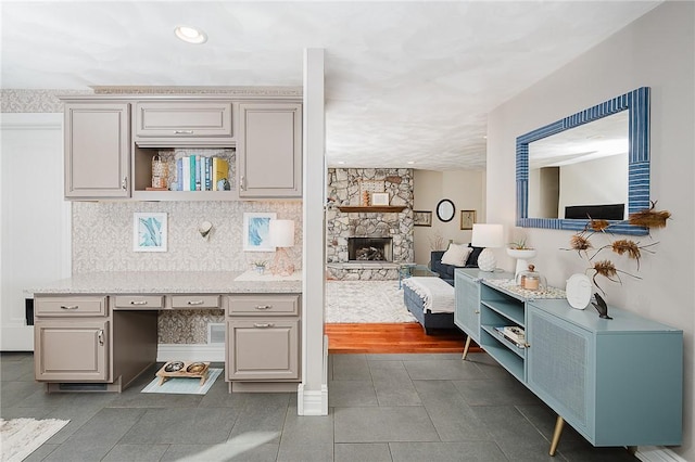 kitchen with tasteful backsplash, a stone fireplace, and tile patterned flooring