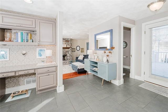 bathroom featuring tile patterned floors, vanity, a stone fireplace, and decorative backsplash