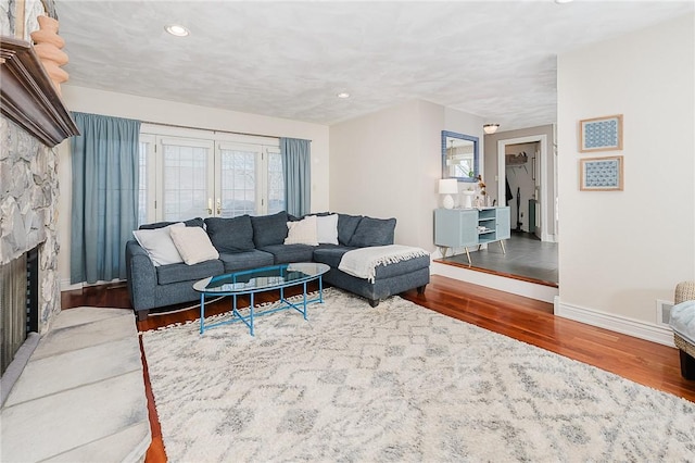 living room featuring a stone fireplace and hardwood / wood-style floors