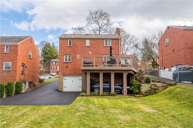 rear view of property with a garage, a wooden deck, and a yard