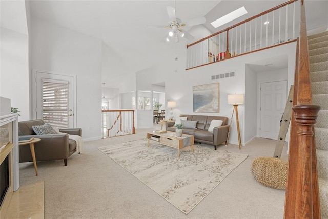 carpeted living room featuring ceiling fan, a healthy amount of sunlight, and a towering ceiling