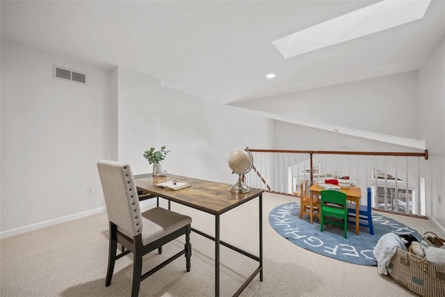 home office with light colored carpet and vaulted ceiling with skylight